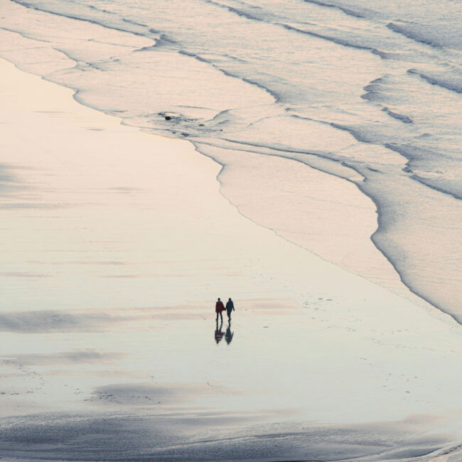 Sandy beach in the evening with couple walking in distance.